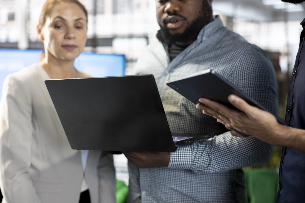 Manager enjoying chat in office, building and maintaining strong relationships with business partners, looking at metrics on laptop. Company director showing shareholders data on notebook